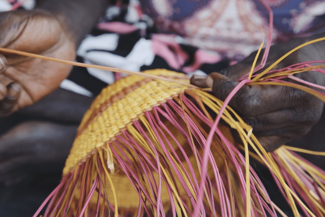 A person threading a woven piece of art.